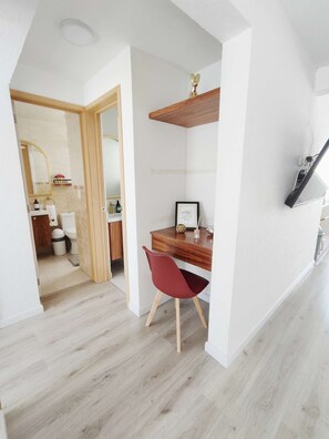 Un intérieur moderne avec un bureau en bois, une chaise rouge et un téléviseur blanc fixé au mur.