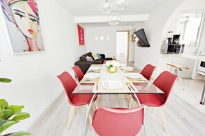 Un espace repas moderne avec une table en verre, des chaises rouges et un vase central.