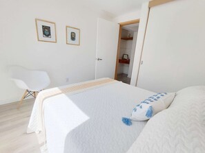 Un dormitorio con una cama, una silla y dos cuadros en la pared.