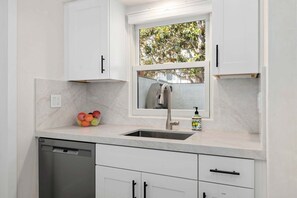 A kitchen with a built-in dishwasher, a sink with a faucet, and a window above the sink.