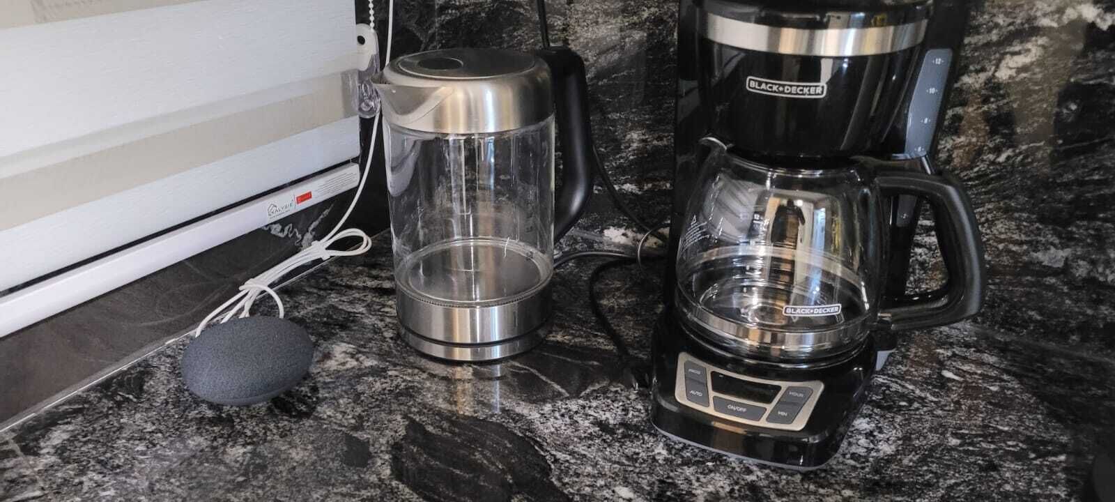 A kitchen with a coffee maker, a kettle, and a sponge on a granite countertop.