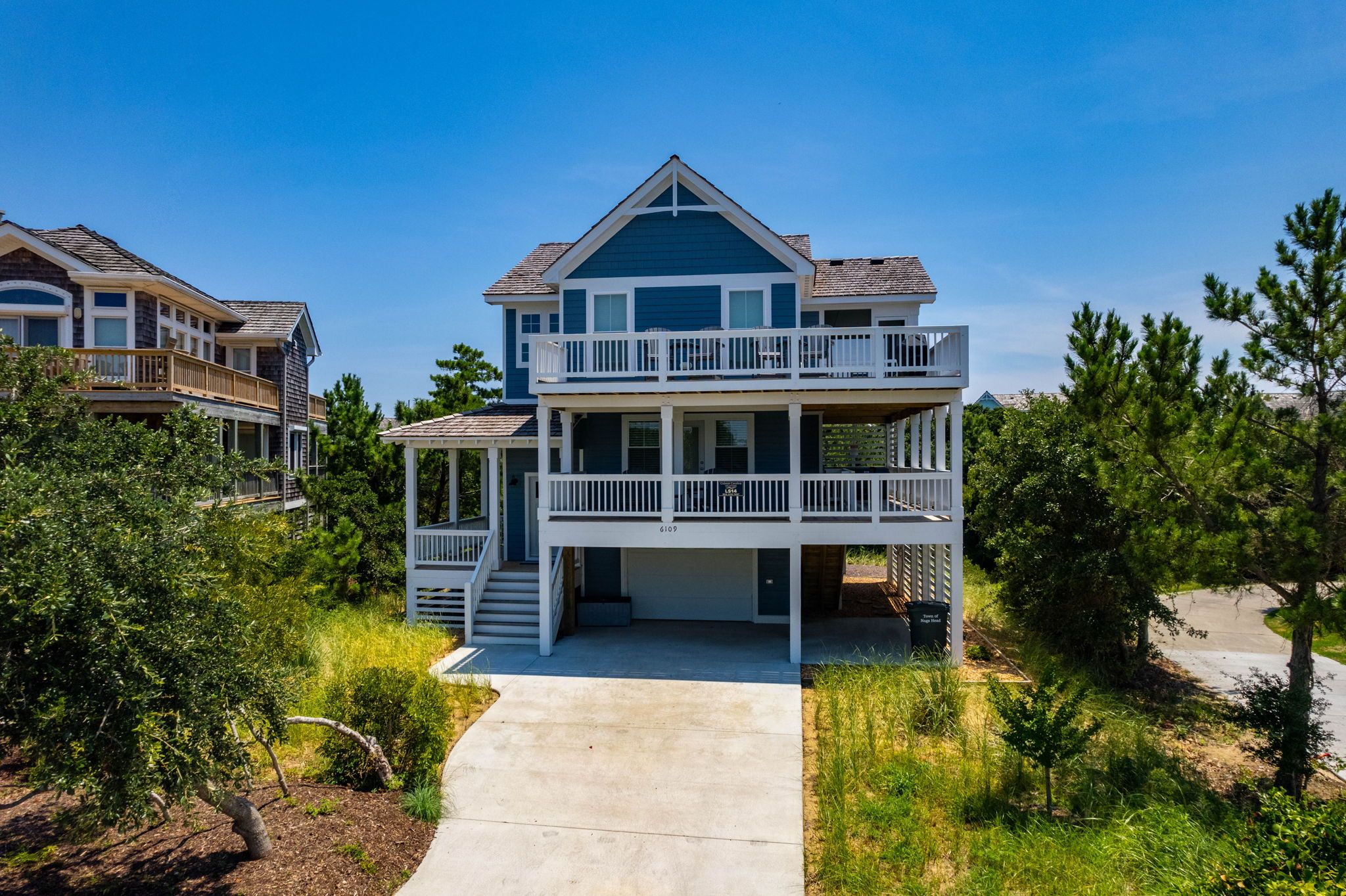 A two-story beachfront house with a covered porch and a balcony.
