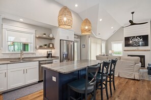 A modern kitchen with white cabinets, a central island, and pendant lighting.
