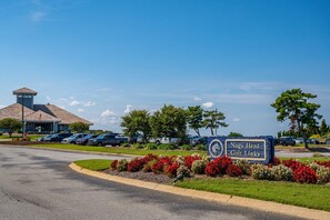 A golf course sign with "Nags Head Golf Links" written on it, surrounded by a landscaped area with red and white flowers. - Shelly Shores - Hot tub, community pool & tennis courts, great views (Nags Head)