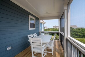 A covered outdoor area with a table and chairs, a window, and a view of the surrounding neighborhood. - Shelly Shores - Hot tub, community pool & tennis courts, great views (Nags Head)