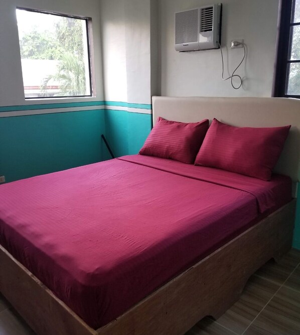A bed with a wooden frame and a teal and white wall.