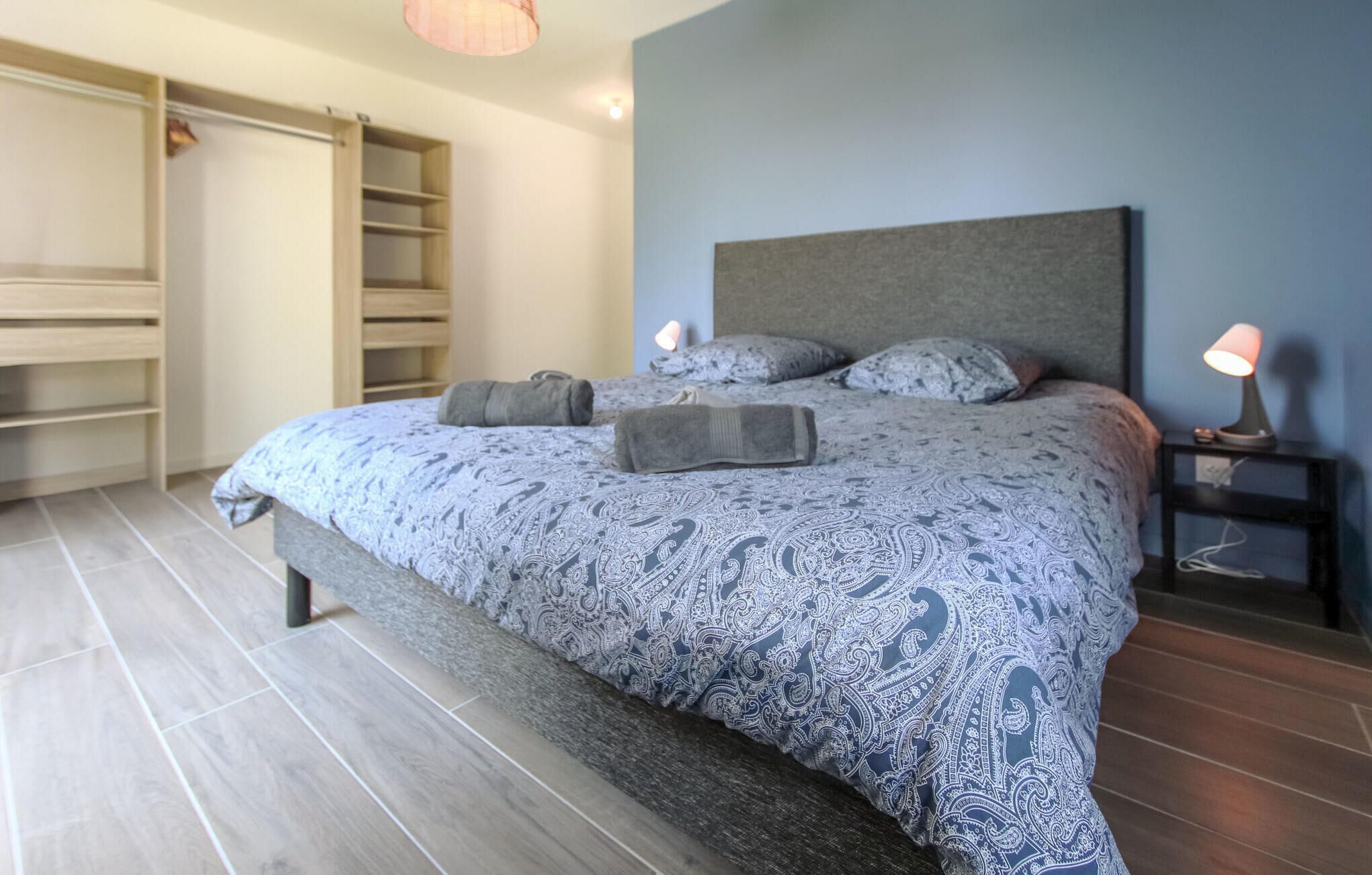 Une chambre à coucher avec un grand lit, une armoire et une table de chevet avec une lampe.