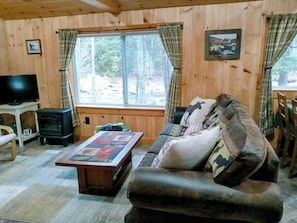 L'interno accogliente di una baita con un divano, un tavolo con una coperta, un televisore e un camino.