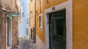 A narrow street with buildings on either side, a cobblestone path, and a door with the number 9.