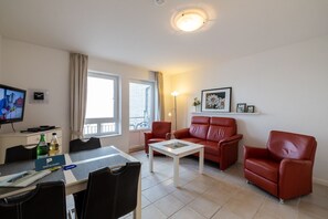 Una sala de estar amoblada con sofá, sillones, una mesa de centro, televisor y un comedor con sillas y mesa.