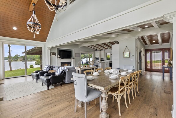 A spacious dining area with a wooden table and chairs, a fireplace, and a view of the outdoors.