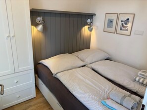Une chambre à coucher comprenant un lit, deux tables de chevet, une armoire et des lampes fixées au mur.