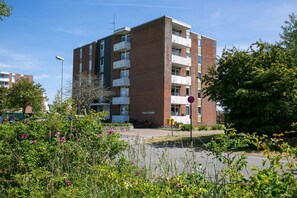 Ein mehrstöckiges Gebäude mit einer Ziegelaußenwand, Balkonen und einem Schild mit der Aufschrift 'HAUS OLAND'.