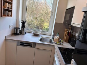 Une cuisine avec une fenêtre, une machine à café, un évier et un lave-vaisselle.