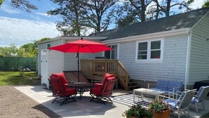 A patio with a table and chairs, a red umbrella, and potted plants. - Bright & Cozy, Yarmouth Cape Top Beaches! (Yarmouth)