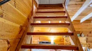 Un escalier en bois mène à un espace cuisine où les appareils sont visibles.