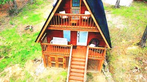 Une cabane en bois à deux étages, dotée d’un balcon, d’un porche et d’un chemin menant à l’entrée.