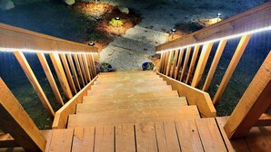 Un escalier en bois, doté de rampes et d’éclairages, qui descend vers un espace jardin.