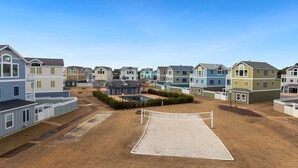 Zona residencial con casas coloridas, una cancha de voleibol y una piscina pequeña.