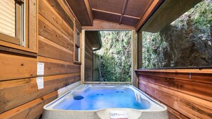 A wooden cabin with a hot tub. - Cozy Family Cabin, Hot Tub, Game Room, 2 King Beds Near Dollywood, Pet Friendly (Pigeon Forge)