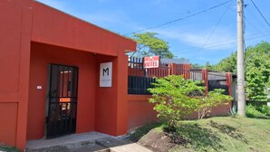 Un edificio rojo con una puerta negra y un letrero con la letra 'M' en mayúsculas.