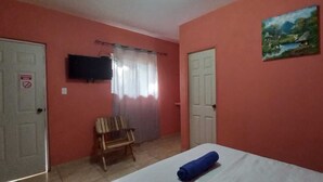 Una habitación con una cama, un banco, un televisor y un cuadro en la pared.