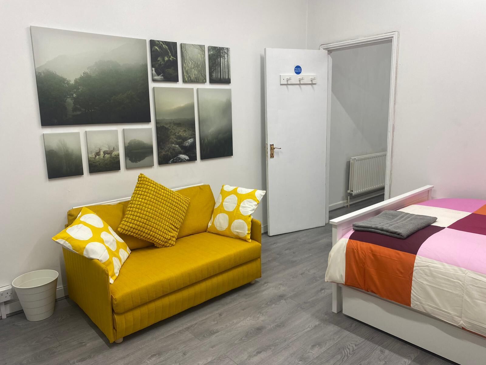 Una stanza con un divano, un letto, una porta e una parete decorata con immagini.