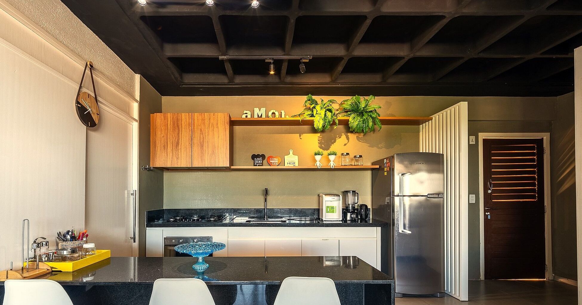 Une cuisine moderne dotée d’un îlot central, d’appareils électroménagers en acier inoxydable et d’un meuble en bois au-dessus du plan de travail.
