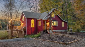 A red brick house with a porch, a wooden deck, and a stone fountain. - kids secret room, Canoes/Kayaks, fire pit, ev charger. (Center Harbor)