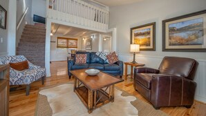 A spacious living room with a high ceiling, a staircase leading to an upper level, and a large window. - Cozy Tucked Away Log Cabin- Lake/Mountain views! (Lake Lure)