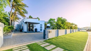 A modern building with a flat roof, large windows, and a paved entrance area. - Villa Cocolishi:Luxe Pool Retreat 5 Min->Beaches (Noord)