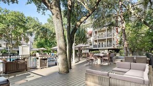 Une terrasse extérieure avec des meubles en osier, un barbecue et un espace aménagé au bord de la piscine.