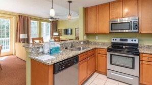 Une cuisine dotée de plans de travail en granit, d’armoires en bois, d’un lave-vaisselle, d’un four à micro-ondes et d’une cuisinière.