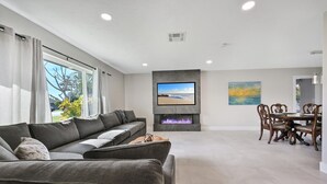 A modern living room with a sofa, a flat-screen TV, a fireplace, and a dining area with wooden chairs. - PROMO 5% WEEKLY AND 10% MONTHLY DISCOUNT
Tropical Dream House with Pool (Naples)