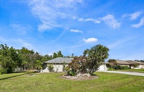 A residential area with houses, a well-maintained lawn, and a clear blue sky.