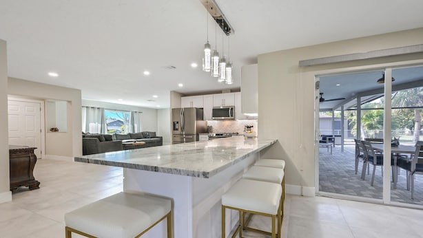 A modern kitchen with a marble island, stainless steel appliances, and a dining area with outdoor seating. - PROMO 5% WEEKLY AND 10% MONTHLY DISCOUNT
Tropical Dream House with Pool (Naples)