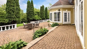 A patio with a brick floor, a white fence, and a seating area with chairs and a table. - Mulgrave Vila (Mulgrave)