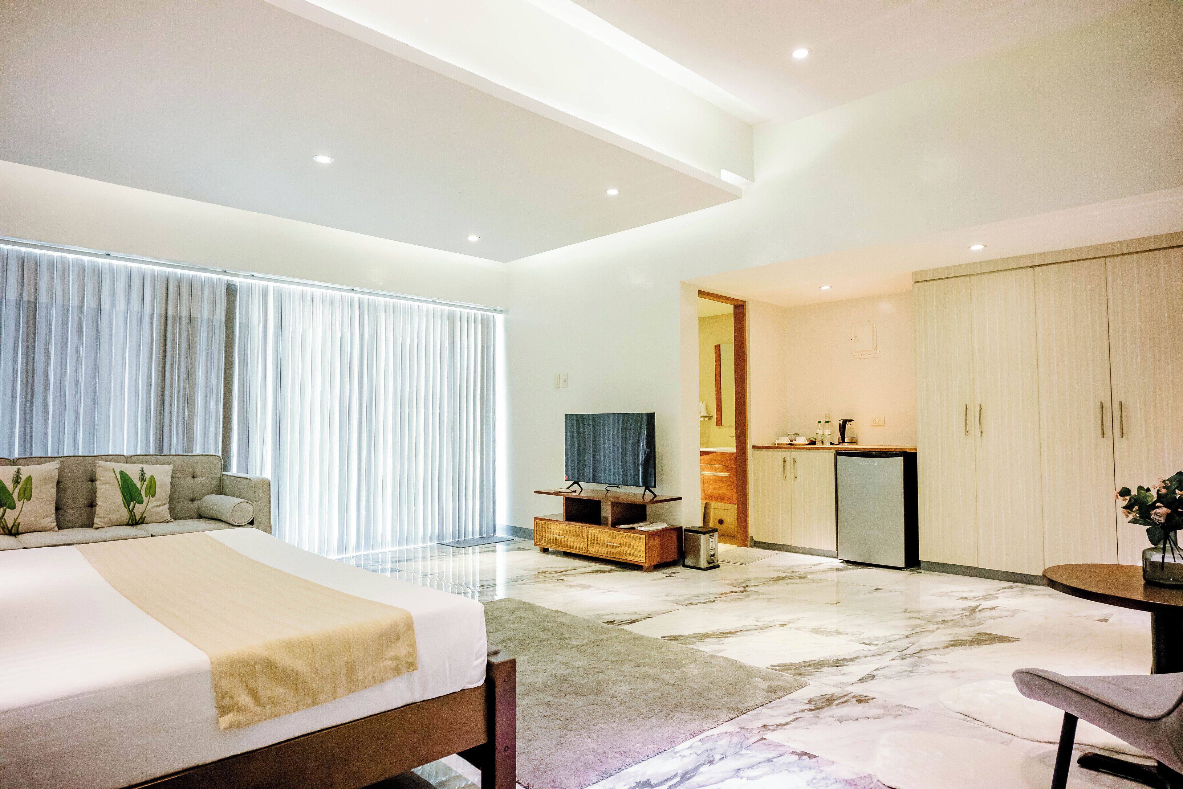 Une chambre d’hôtel moderne dotée d’un grand lit, d’une télévision à écran plat, d’un coin repas et d’une cuisine.
