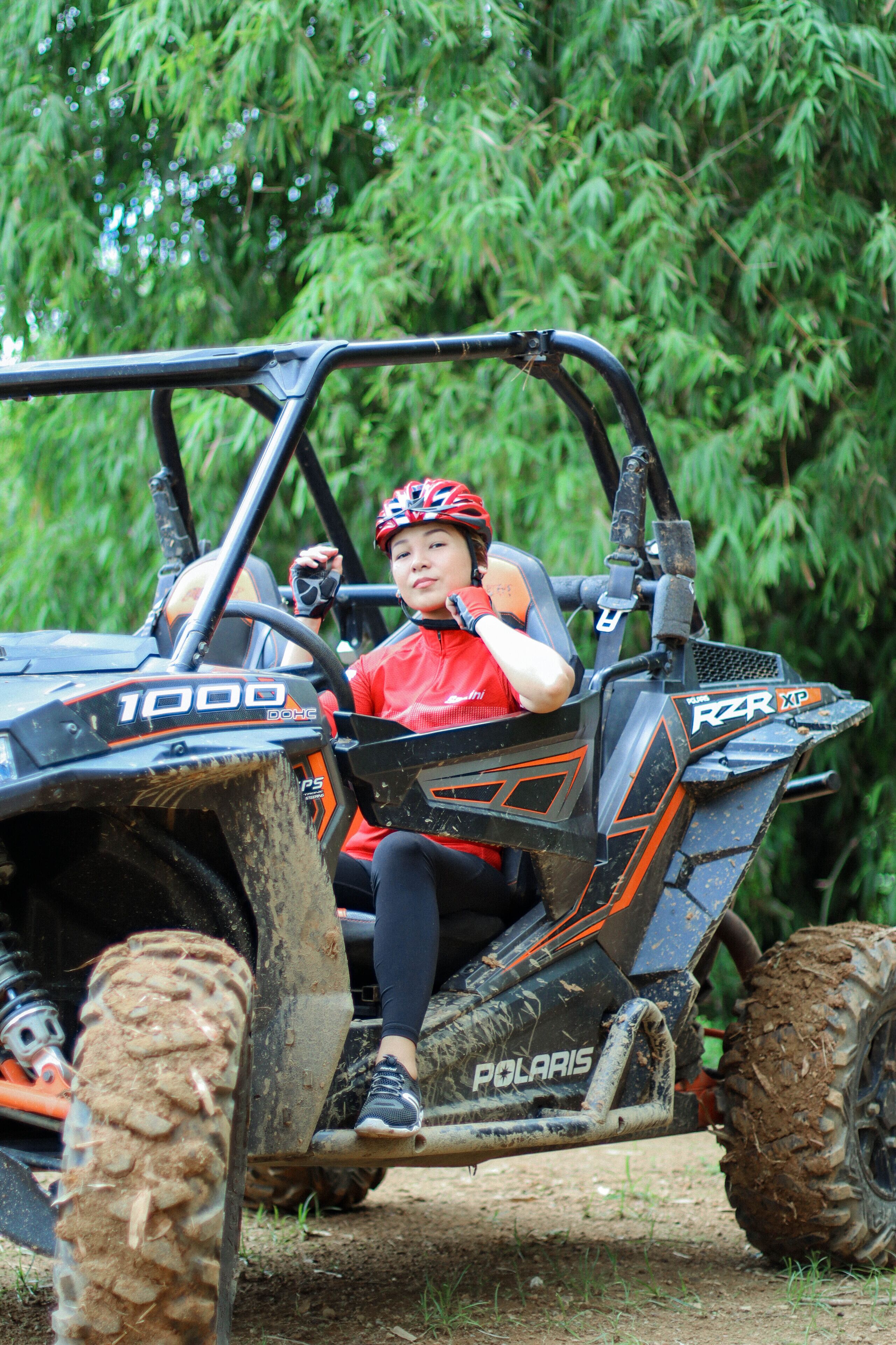 A person in a red shirt and helmet sitting in a Polaris 1000 ATV.