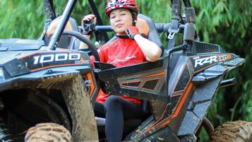 A person in a red shirt and helmet sitting in a Polaris 1000 ATV.