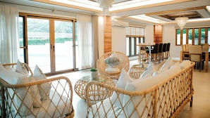 A spacious room with wicker furniture, large windows, and a chandelier. - Estancia De Lorenzo (San Mateo)