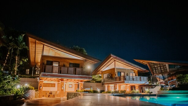 A modern hotel with a pool, multiple balconies, and a well-lit outdoor area. - Estancia De Lorenzo (San Mateo)