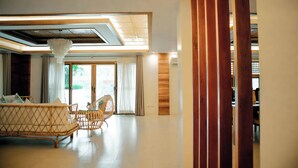 A spacious room with a sofa, wicker chairs, a ceiling fan, and a large window with curtains. - Estancia De Lorenzo (San Mateo)