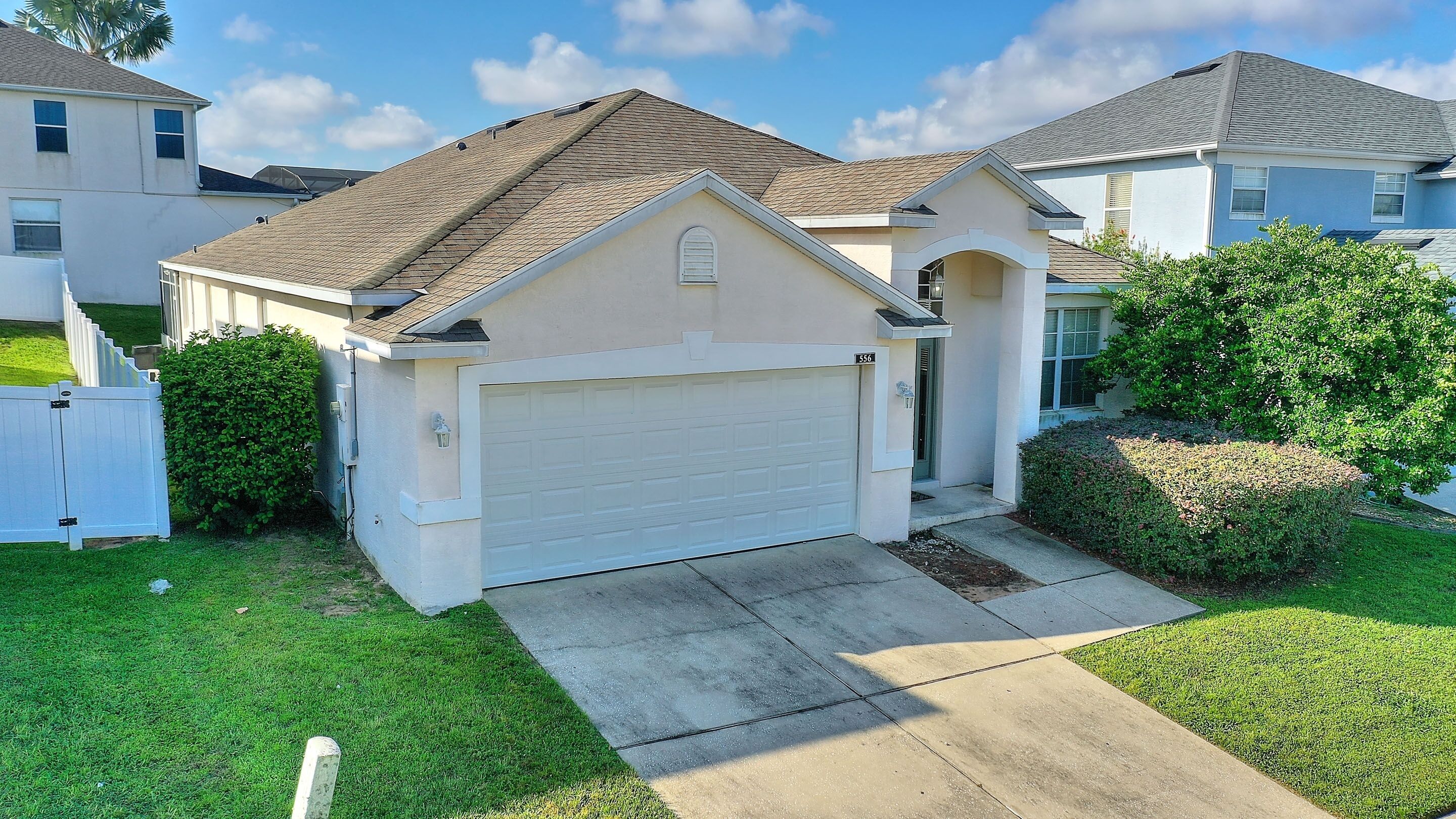 A single-story house with a white garage door, a small porch, and a well-maintained lawn.