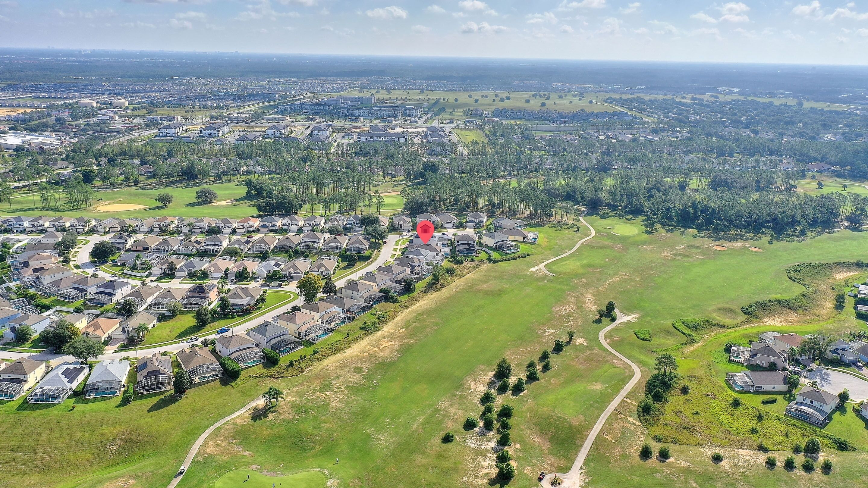 An aerial view of a residential area with houses, roads, and a golf course.