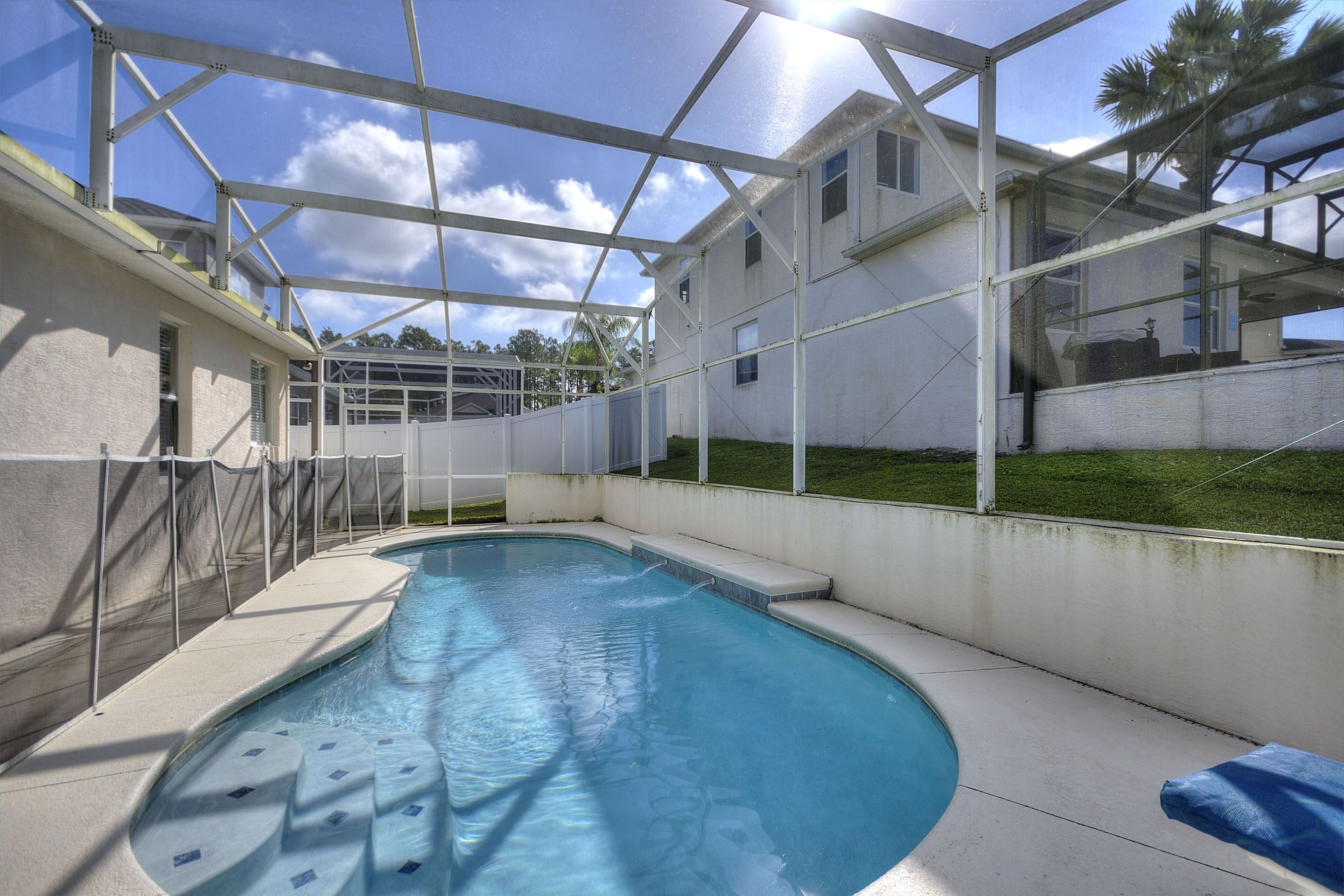 En swimmingpool med et glaskuppel, omgivet af et hvidt hegn og en betonflisebelagt terrasse.