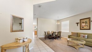 A living room with a dining area, a sofa, a coffee table, and a mirror.