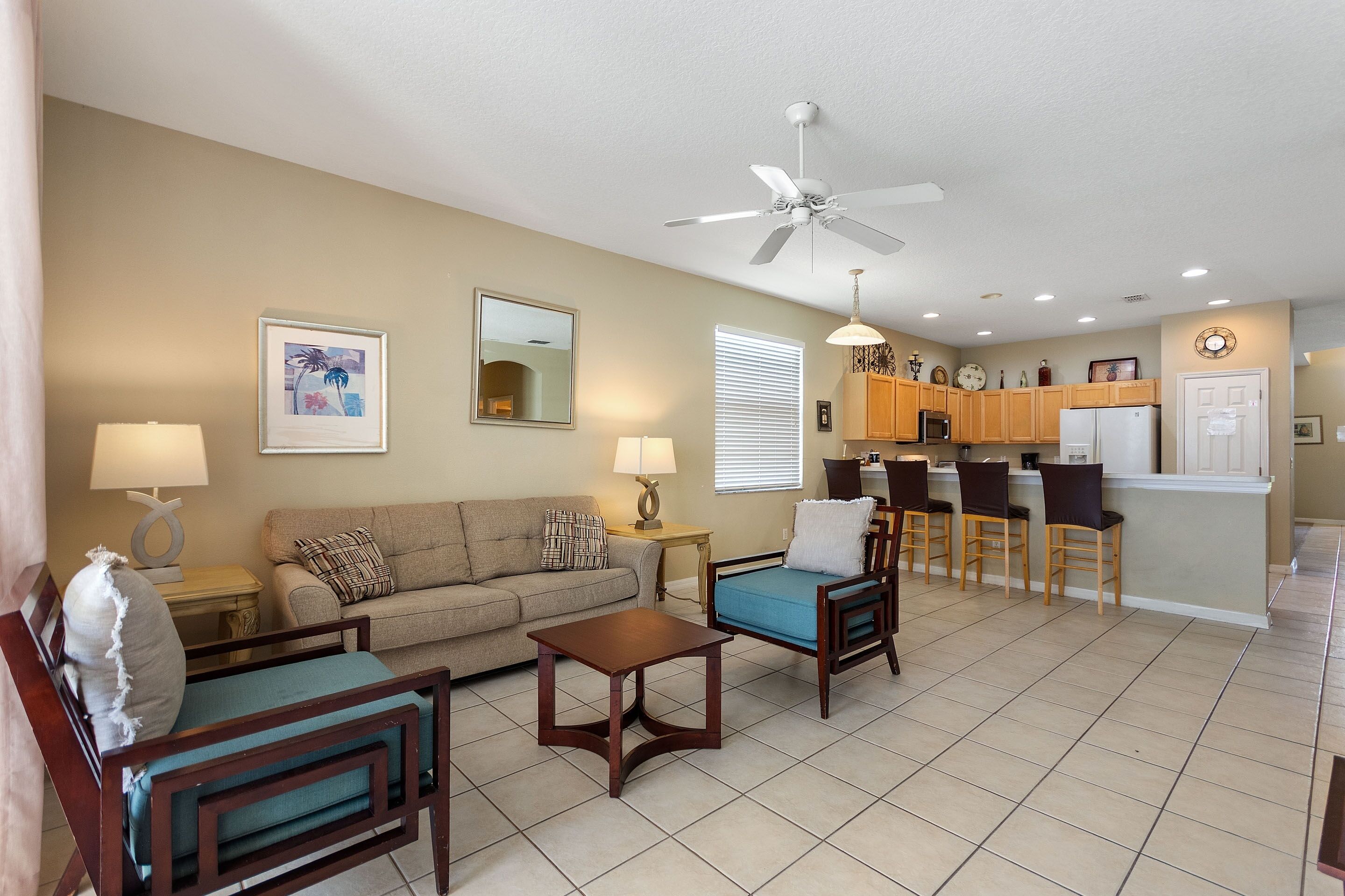A living room with a sofa, chairs, a coffee table, and a kitchen area with a bar and counter.