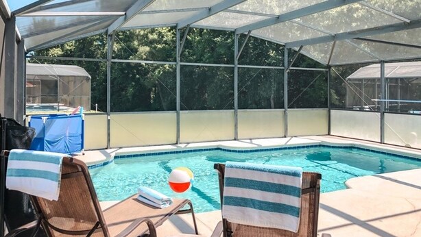 A covered swimming pool with lounge chairs and a hot tub. - Tranquil Hideaway At Sandy Ridge 4 Bedroom Home (Davenport)