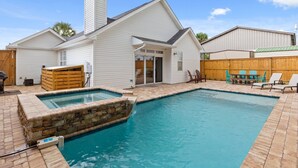 Une maison avec une piscine, une terrasse en bois et un patio couvert.